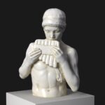 Sculpture représentant un jeune garçon jouant de la flûte de pan.