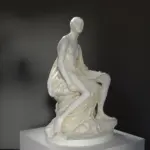 Replica della scultura di Voltaire Nudo al Louvre, evidenziando i dettagli anatomici e la posa dinamica.